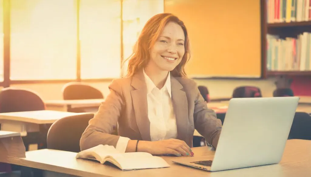 Smiling woman with a computer in a class room.